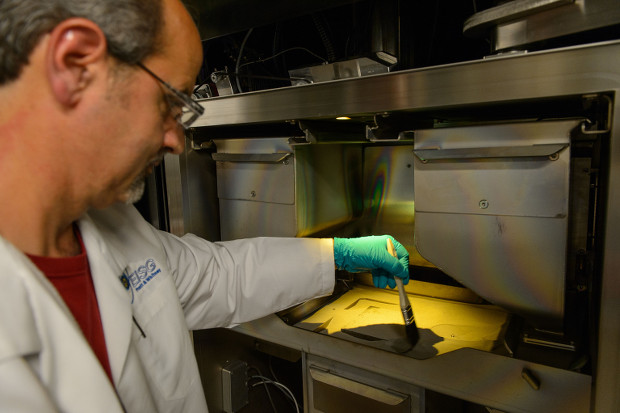 Lou Porretti, a Pratt & Whitney design technician prepares an electron beam melting machine for a new run at the Pratt & Whitney Additive Manufacturing Center at the University of Connecticut on June 26, 2013. (Peter Morenus/UConn Photo)