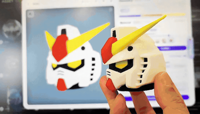Multi-color printed Gundam head beside its on-screen model. 